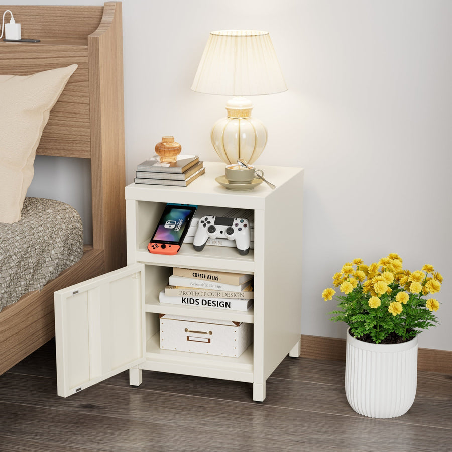 Velador metálico crema con puerta abierta y compartimento superior, junto a una cama de madera con lámpara encendida